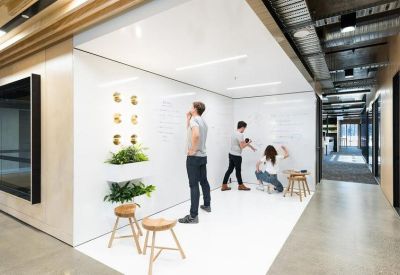 Collaborative brainstorming space with floor-to-ceiling whiteboards and potted plants.