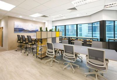 Professional collaborative workspace with long grey tables and ergonomic chairs near windows.