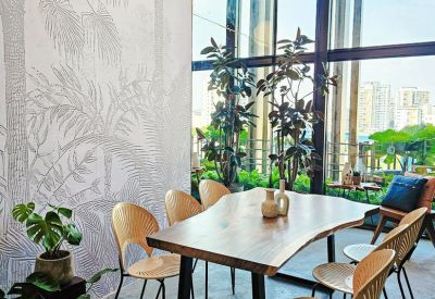 Communal dining area featuring a live-edge wooden table, stylish chairs, and palm tree wall art.
