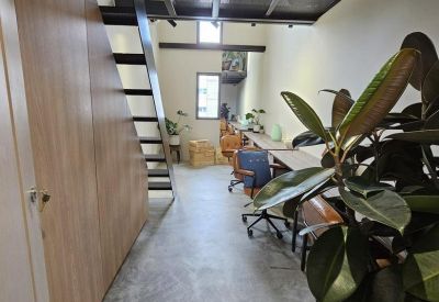 View from an entryway showing a modern workspace with concrete floors and a mezzanine structure.