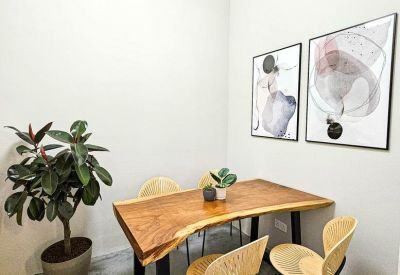 Small meeting area with a natural wood table, designer chairs, and abstract wall art.