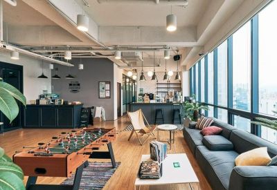 Spacious lounge area with a foosball table, blue sofa, and large windows with city views.