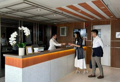 Reception area with a light marble desk, warm wood paneling, and elegant white orchids.