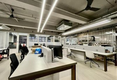 Bright open-plan workspace featuring long white desks and ergonomic black chairs.