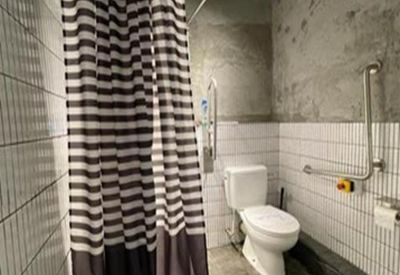 Accessible restroom with white tiling and concrete walls.