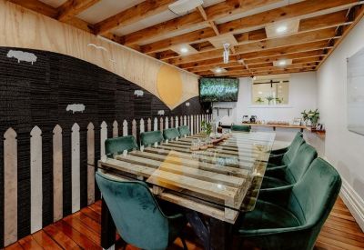 Casual breakout room with an industrial aesthetic, featuring a long table and green velvet seating.