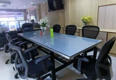 Spacious meeting room featuring a glass-top conference table and black mesh chairs.