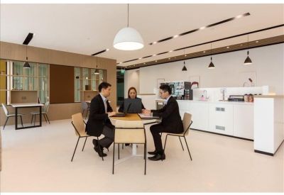 Casual breakout area where colleagues are meeting around a circular table in a bright, modern setting.