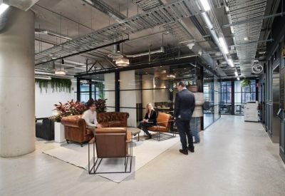 Lounge area with tan leather armchairs and a glass-walled meeting room in the background.