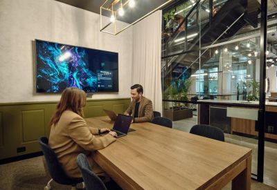 Private meeting room with a wooden table, ergonomic chairs, and a large wall-mounted monitor.