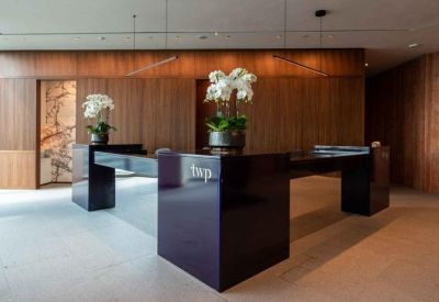 Modern dark wood reception desk with white orchid arrangements and warm lighting.