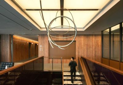 Close-up of a marble staircase and modern sculpture beneath a luminous skylight ceiling.