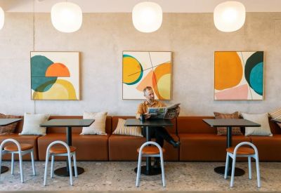 Cozy lounge area featuring orange leather seating, vibrant abstract art, and round pendant lights.