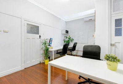 Internal office space with white desks, ergonomic chairs, and potted plants.