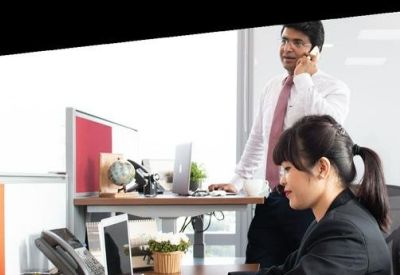 Employees working at ergonomic desks with orange and red partitions.