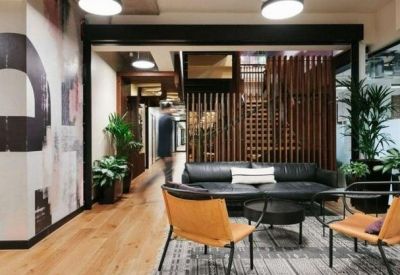 Modern lounge area featuring a black leather sofa, tan leather chairs, and a wooden slat room divider.