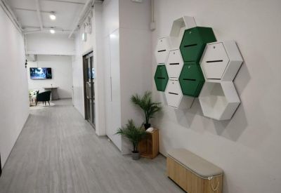 Modern hallway with a unique green and white honeycomb storage wall and light wood seating.