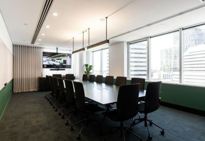 Spacious boardroom with a long dark table, black chairs, and large windows with city views.
