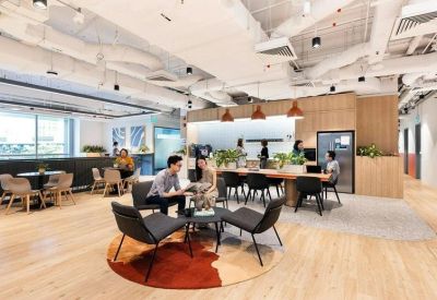 Spacious communal lounge with diverse seating, warm wood floors, and industrial ceilings.