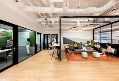 Glass-walled meeting and breakout zones featuring a comfortable seating area on a red rug.