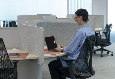 Person working at an open-plan workspace with individual desks.