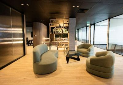 Spacious communal lounge with curved light green sofas and a wooden coffee table.