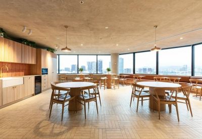 Spacious communal dining area with round tables, wood flooring and kitchen facilities.
