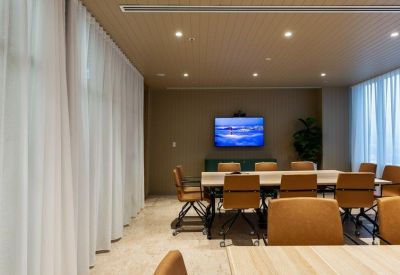 Professional meeting room with leather chairs and wall-mounted display screen.