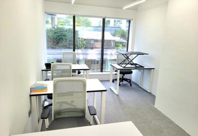 Bright private office featuring four white desks and grey mesh chairs.