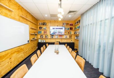 Meeting room with a long white table, wooden walls, and a large whiteboard.