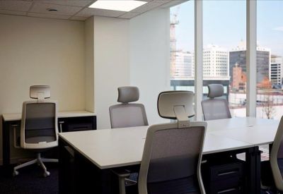 Private office suite with multiple grey ergonomic chairs and large city-view windows.