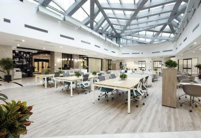Expansive communal coworking area featuring a dramatic geometric glass atrium ceiling and light wood floors.