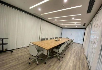 Long wooden boardroom table with modern white chairs and recessed linear lighting.