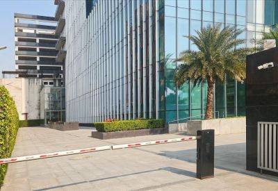 Modern glass exterior of the Sovereign Corporate Tower with a secure gated entrance and palm trees.