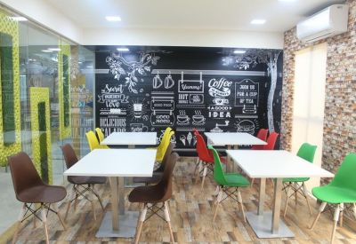 Communal break area featuring a chalkboard-style mural and colorful chairs.