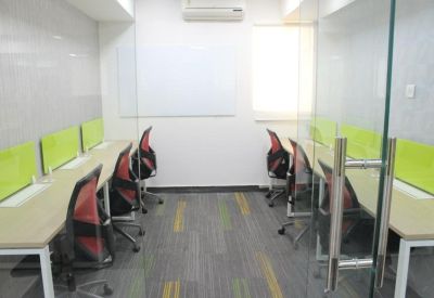 Bright workspace with long rows of desks and vibrant green privacy screens.