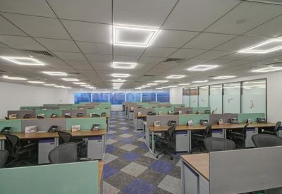 Bright open-plan office space featuring rows of desks with pale green privacy partitions.
