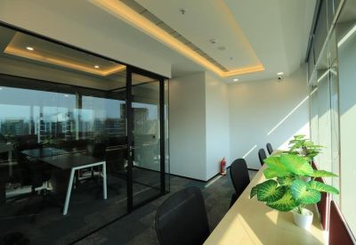 Bright glass-walled private office area with a light wood desk and green plant.