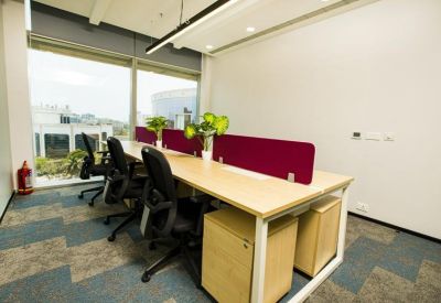 Modern open-plan workspace with multiple desks, maroon privacy dividers, and natural light.