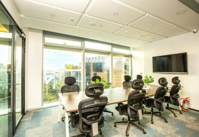 Meeting room with large windows offering city views and black ergonomic chairs.
