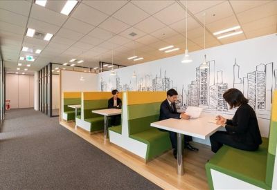 Collaborative workspace featuring green and yellow booths with city skyline wall art.