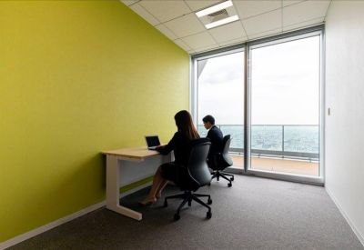 Private office with a lime green feature wall and two workstations near a window.