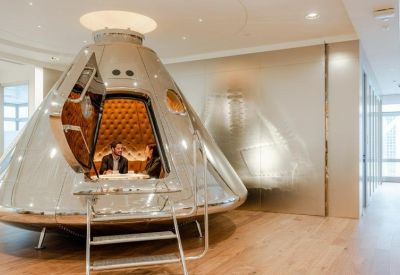 Unique metallic spacecraft-shaped meeting pod on a light wood floor.