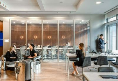 Modern coworking area with glass partitions and people working at tables.