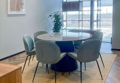 Modern office kitchen area with a sleek marble island and high wooden stools.