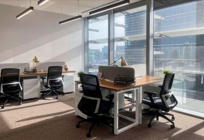 Modern open-plan workspace with multiple desks and floor-to-ceiling city views.