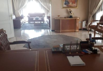 Spacious private office with an ornate wooden desk, leather guest chairs, and built-in shelving.