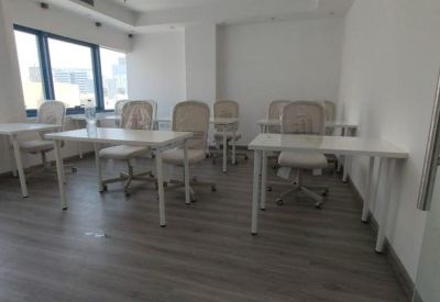 Spacious training room with multiple white desks and mesh-back chairs.