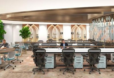 Modern open-plan coworking space with ergonomic chairs, wood flooring, and indoor trees.