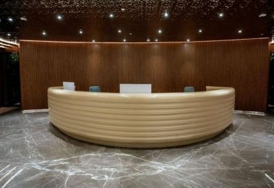 Spacious reception area with a large curved tan desk and dark marble floors.
